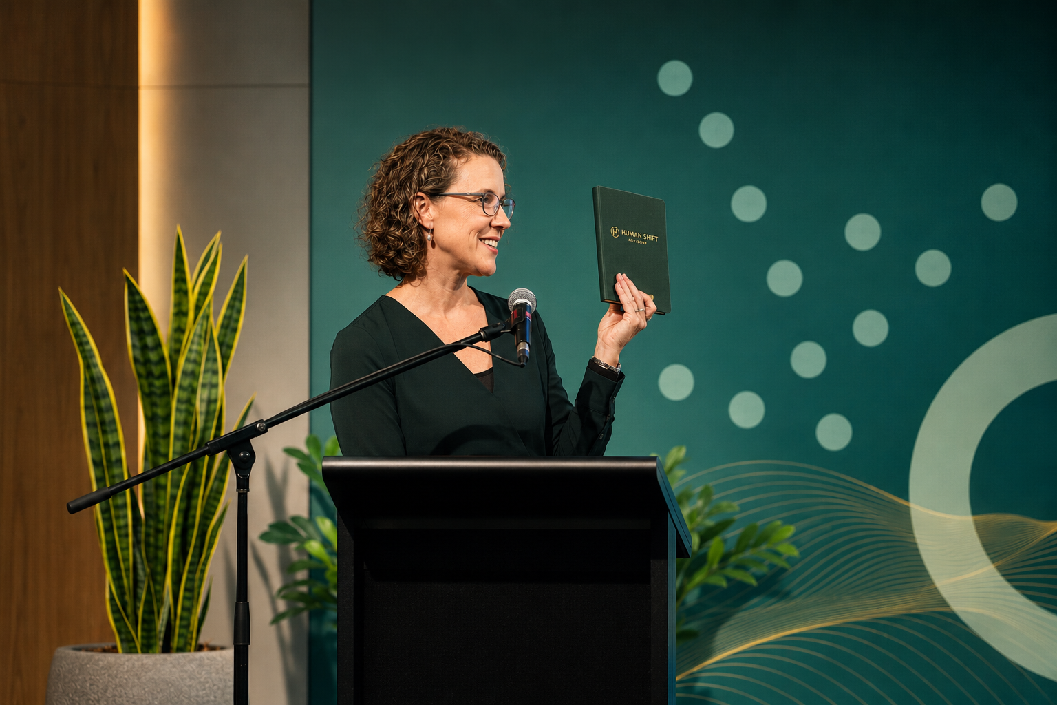 Jo Grubb presenting a keynote on Human-Centric AI while holding a Human Shift notebook during a leadership forum.