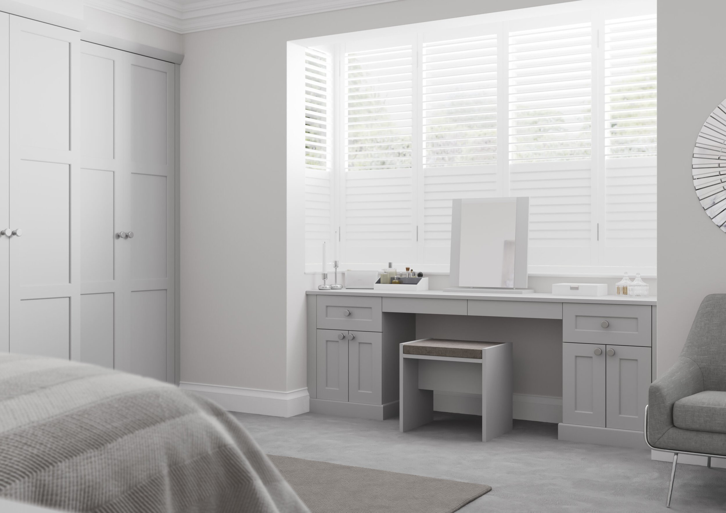 A bright, white bedroom with large window shutters, a vanity table with mirror, and a bed with a striped blanket.