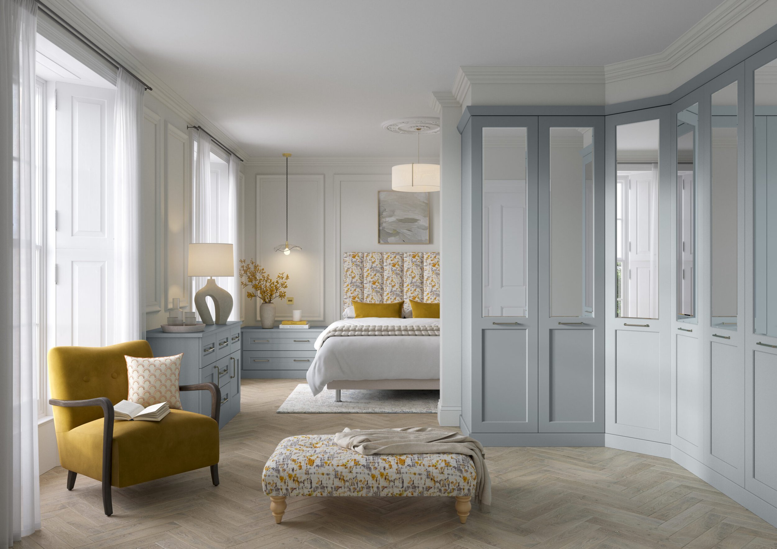 A bedroom with white walls, large windows with sheer curtains, a bed with white bedding and yellow pillows, a blue nightstand with lamps and decorations, a yellow armchair with a throw pillow, and a patterned ottoman
