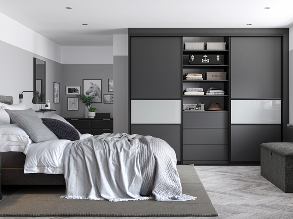 Modern bedroom with a bed, pillows, and a blanket, adjacent to a gray and white closet with open shelves and sliding doors, and framed pictures on the wall.