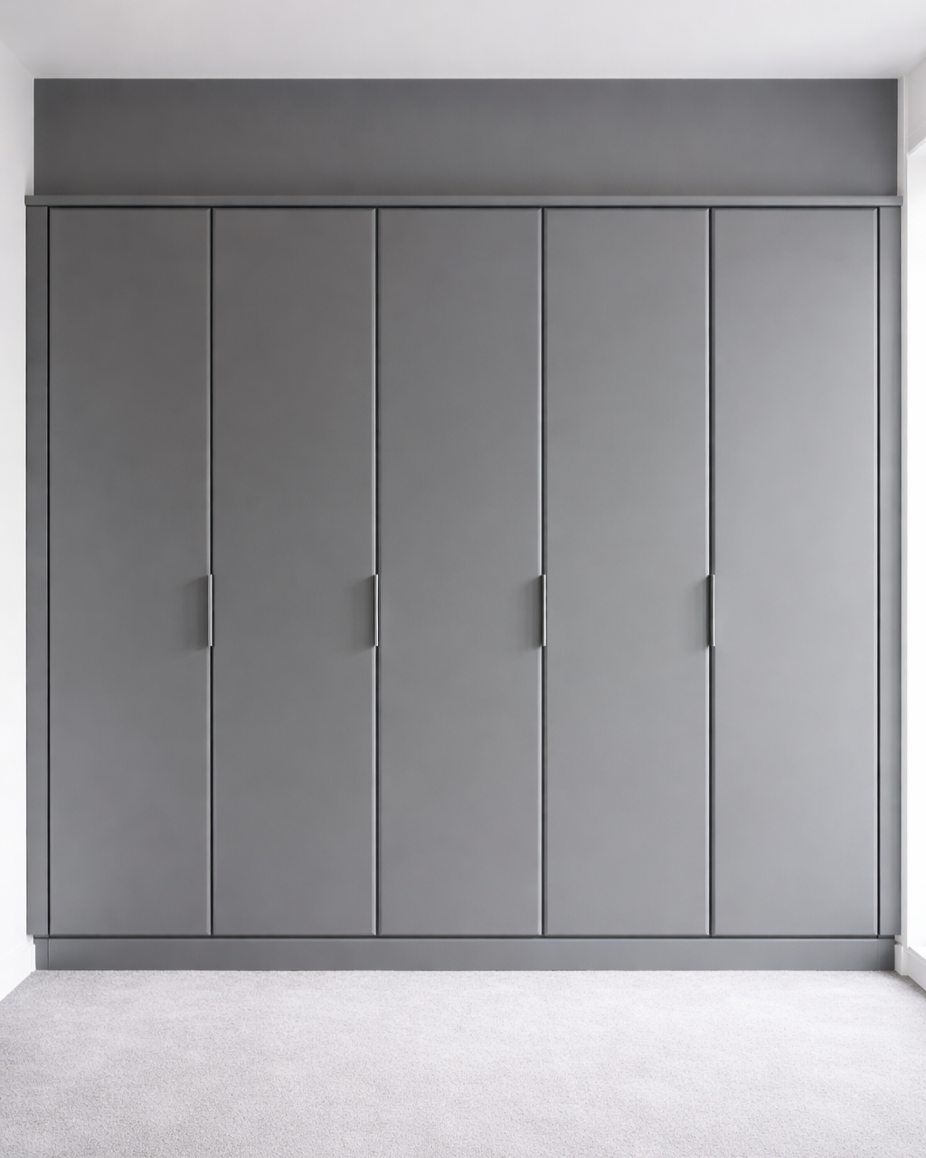 Gray built-in closet with five closed doors in a room with white walls and a white carpet.