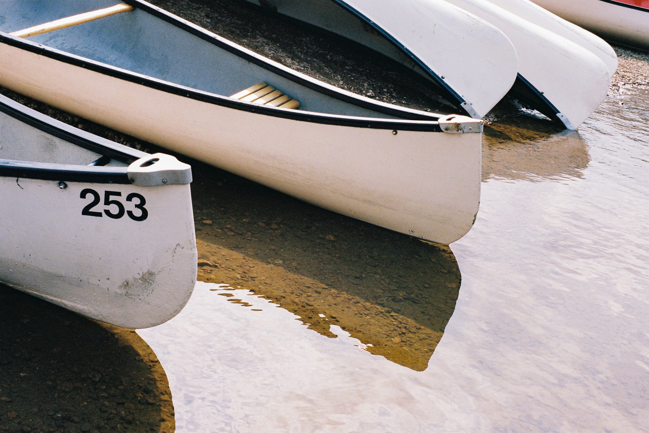 Bateaux en ordre sur le rivage avec reflets dans l'eau.