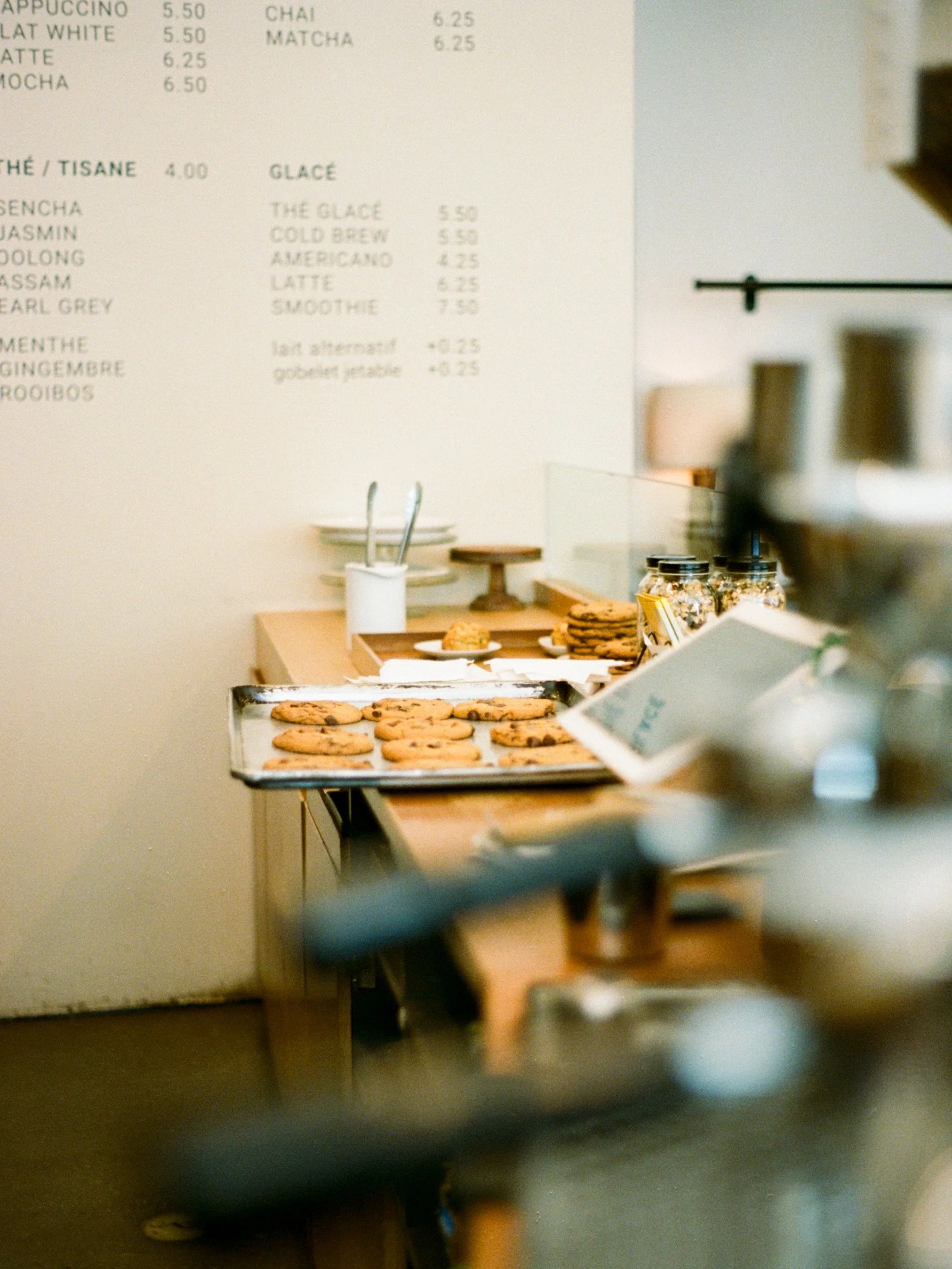 Vitrine à cookies posée sur un comptoir dans un café, avec un menu en arrière-plan.