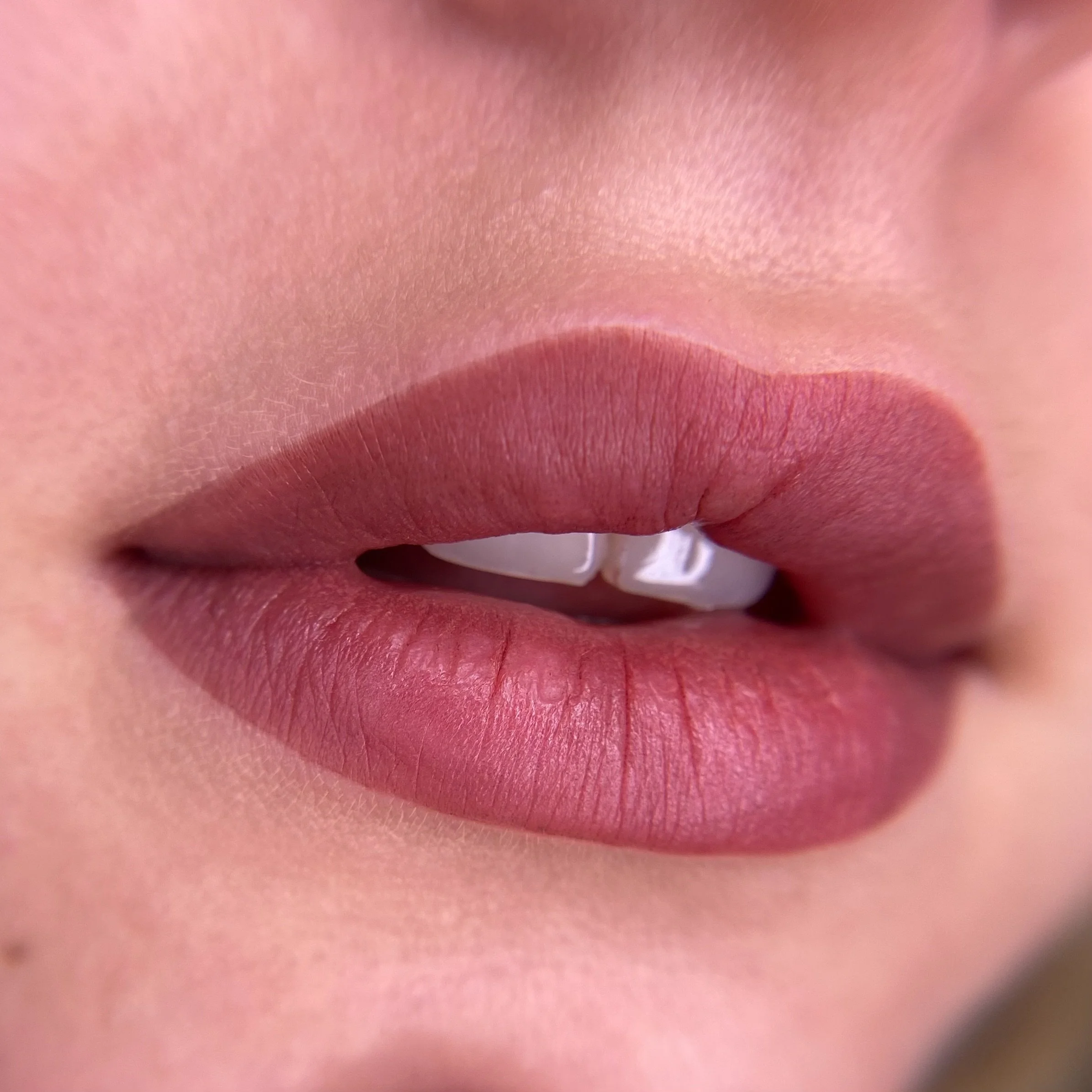 Zoom su labbra rosa e denti bianchi in primo piano.