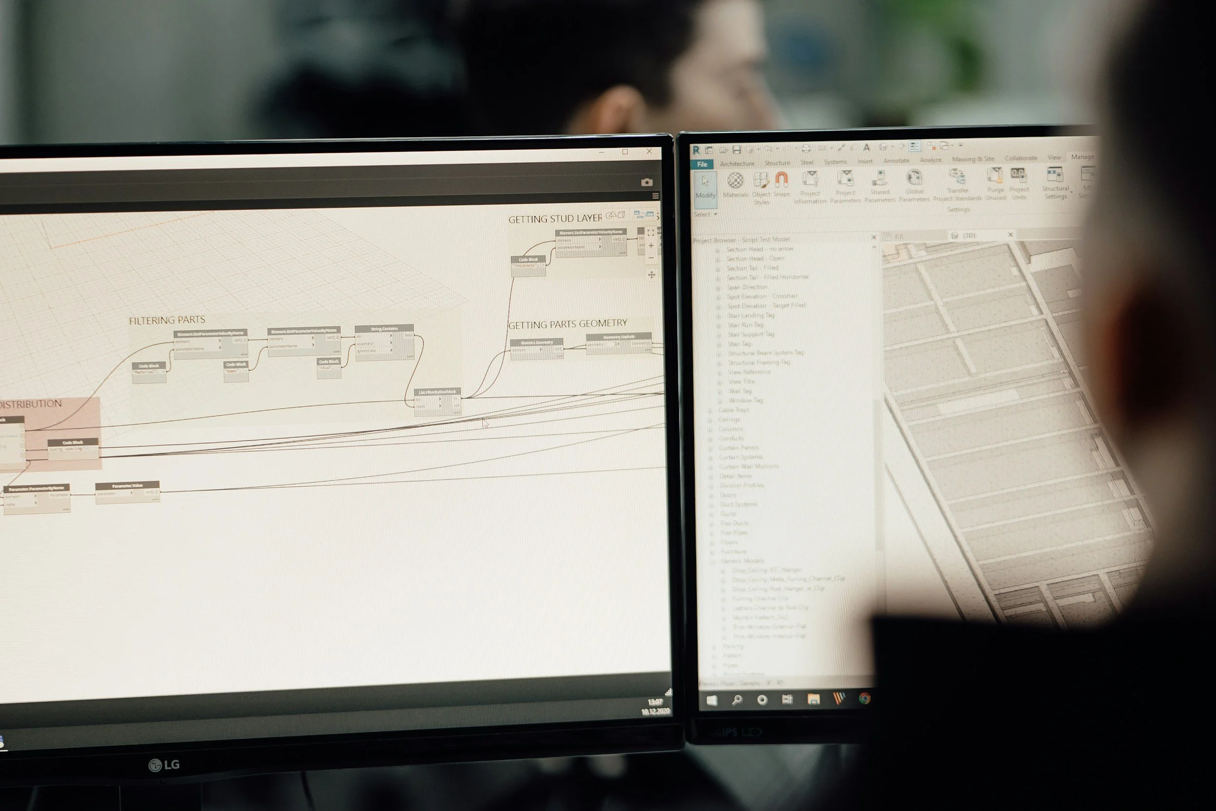Close-up of a dual computer monitor displaying technical design software and architectural plans, with a blurred background of a person's face.