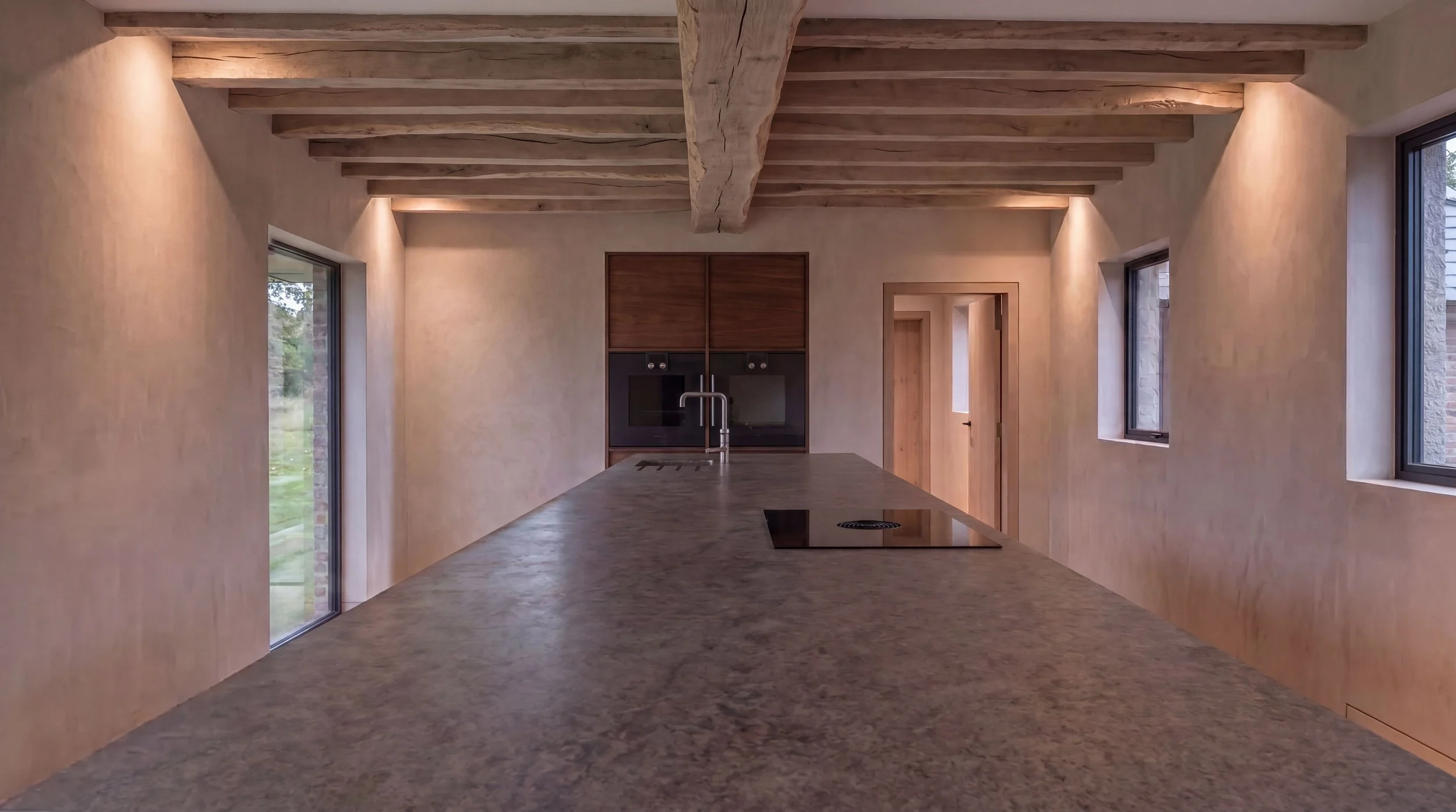 Contemporary kitchen with wood accents, granite countertop island, built-in oven, and large windows with views of greenery outside.