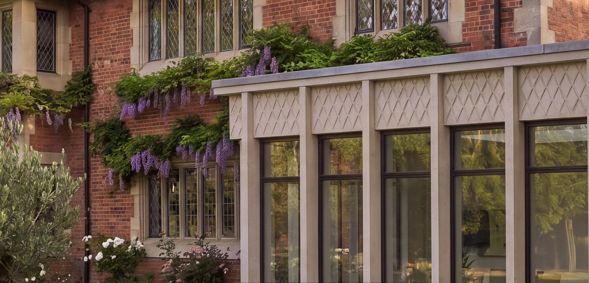 A brick building with large windows, decorated with purple wisteria and green plants on the balcony.