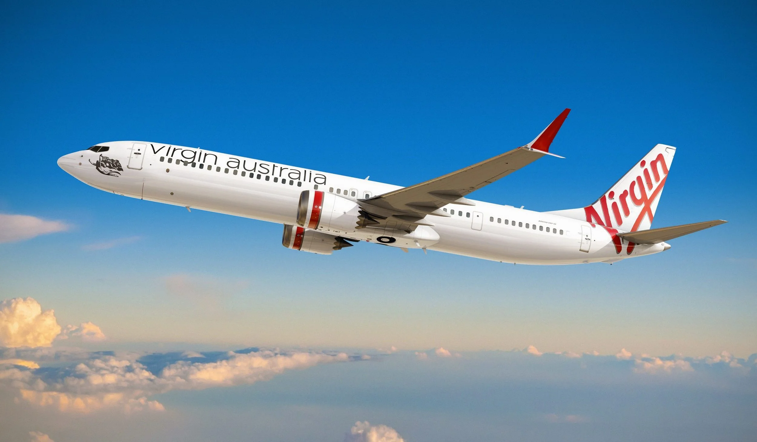 A Virgin Australia airplane flying in the sky above clouds with a clear blue sky.