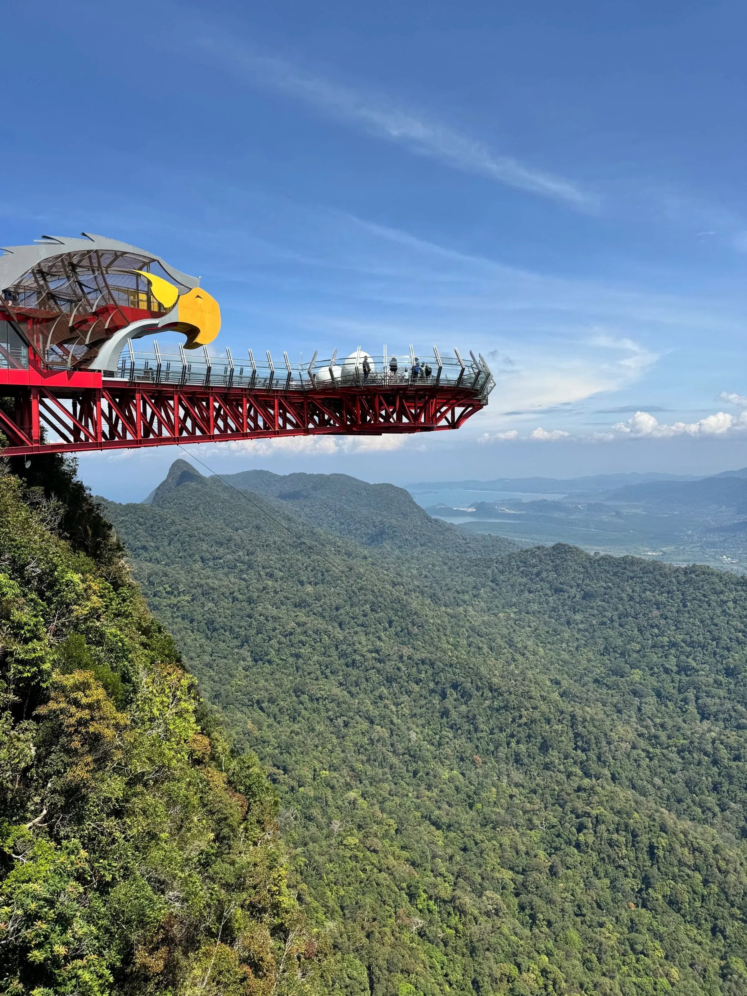 Red observation deck with an eagle sculpture at its entrance, cantilevered over a forested valley.