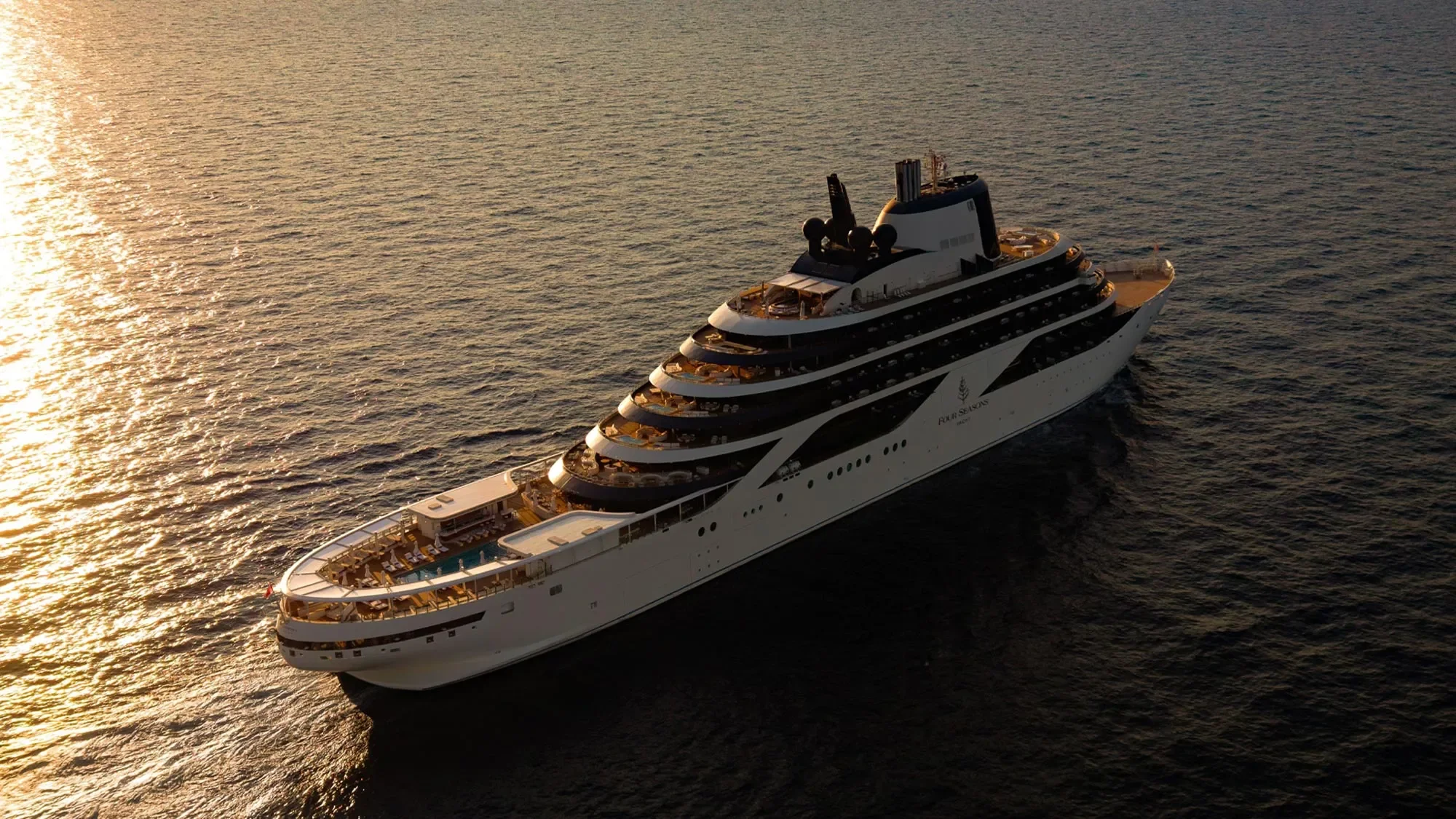 A large luxury cruise ship sailing on the ocean at sunset.