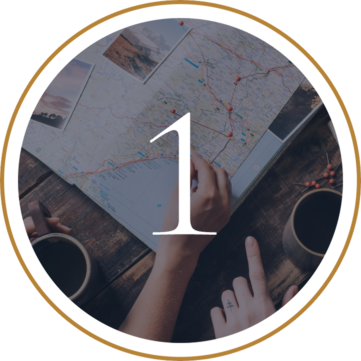 Person planning a road trip with a map, coffee, and snacks on a wooden table.