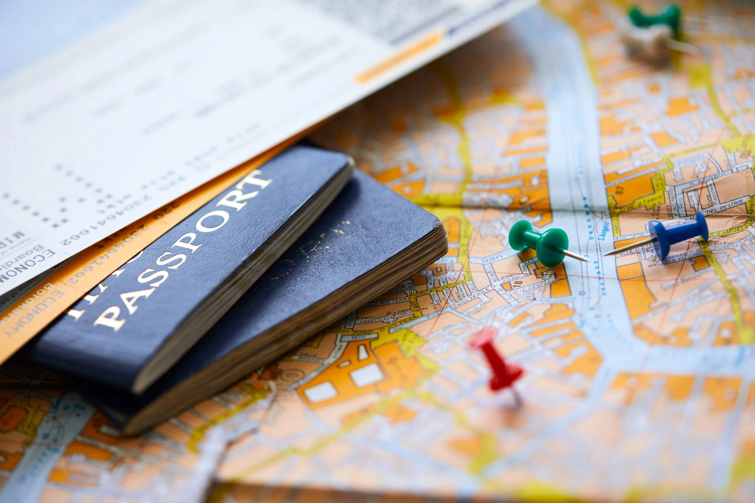 Travel documents, a city map, and pushpins on a table.