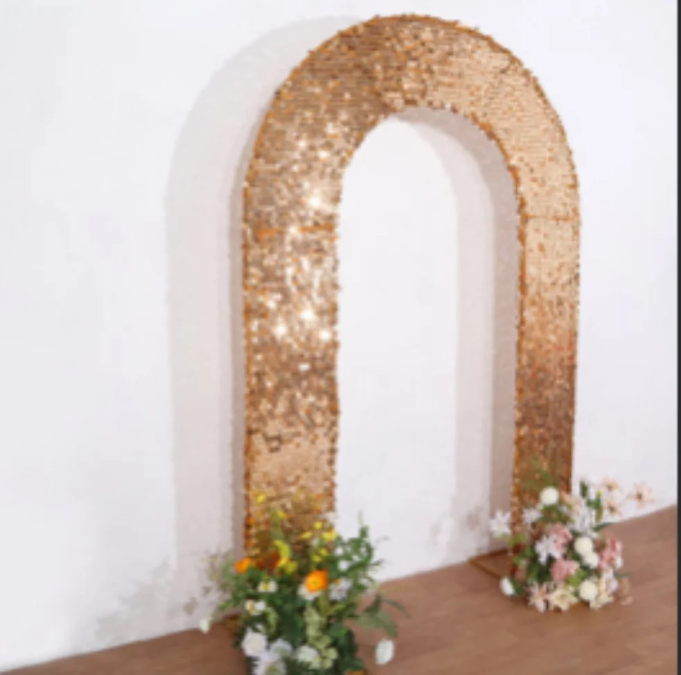 Decorative gold sequined arch with floral arrangements at its base, set against a plain white wall.