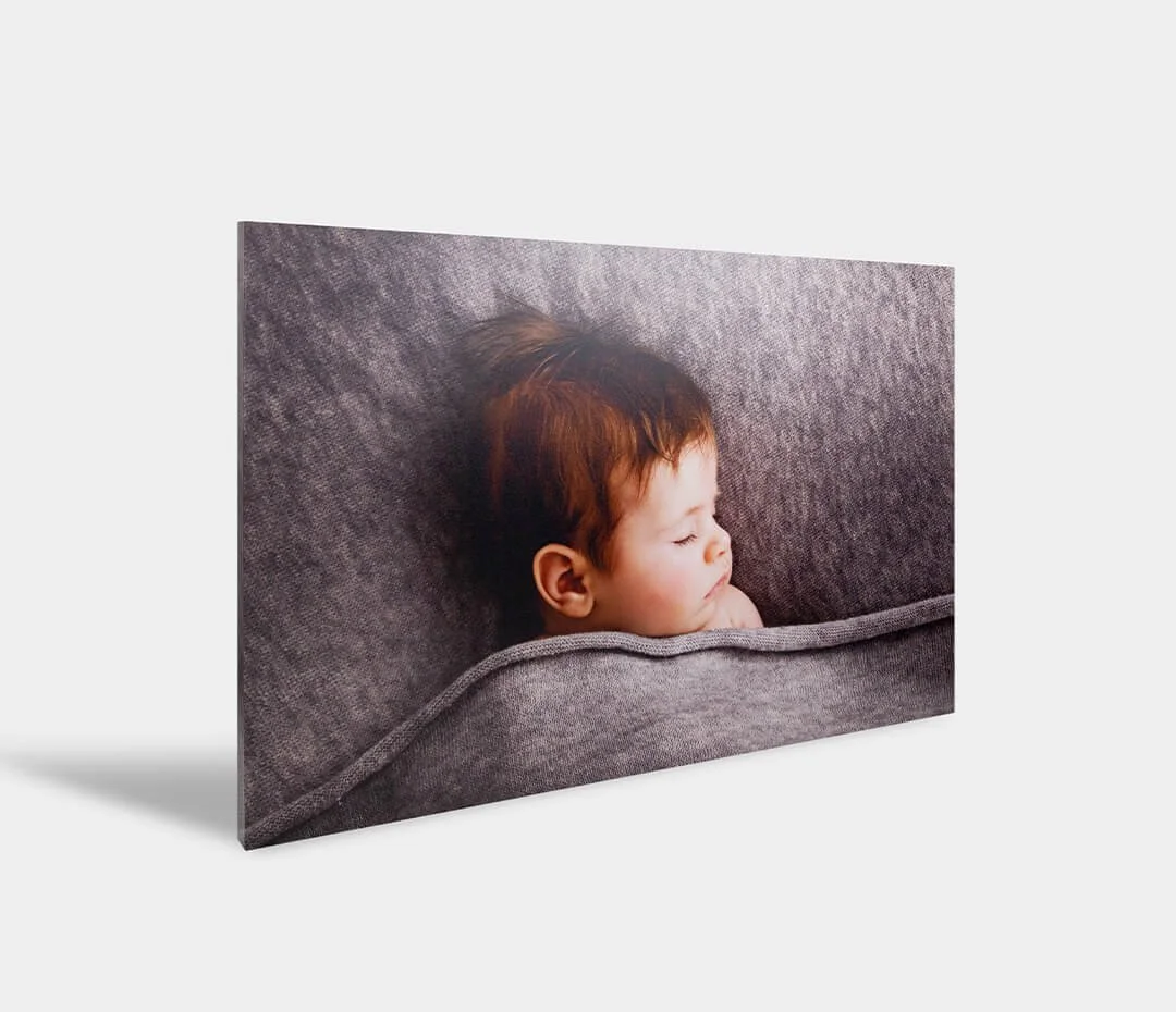 A canvas print of a sleeping child with red hair, peacefully resting on a gray couch.
