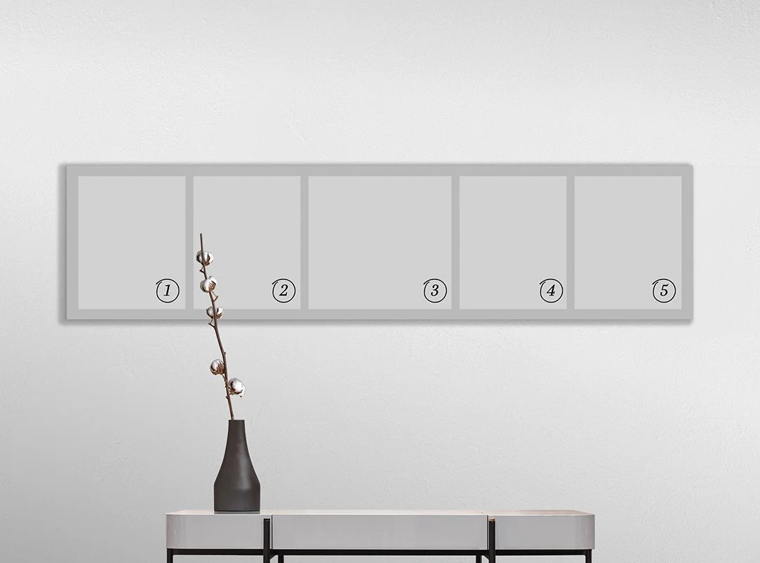 A minimalistic wall decor with a rectangular light gray board featuring five empty labeled compartments, a dark gray vase holding a single branch with buds, placed on a white cabinet.