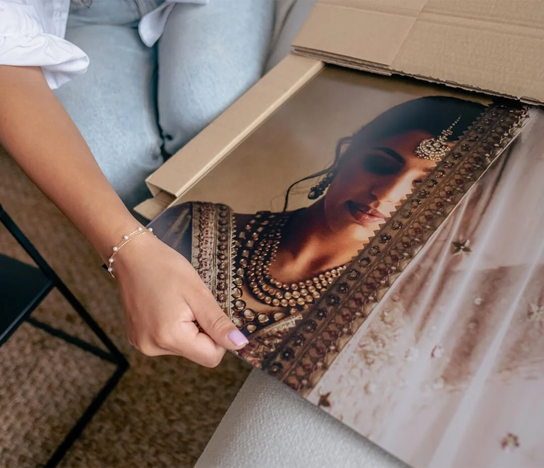 Person holding a framed portrait of a woman wearing traditional jewelry and attire.