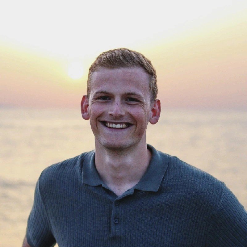 Een lachende man op het strand tijdens zonsondergang.