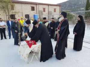 A group of people dressed in formal and religious attire gathered outdoors around a table with a religious ceremony taking place.