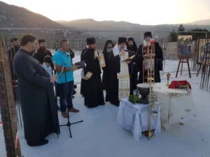 Group of people participating in an outdoor religious or ceremonial event at sunset, with a priest or religious leader leading the ceremony.