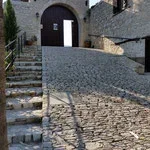 Stone courtyard with steps leading to a white door in a stone building