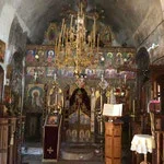 Interior of an ornate church with religious icons, gold accents, and a chandelier.