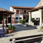 An outdoor courtyard with potted plants, a fountain, and a two-story building with balconies and a tiled roof.