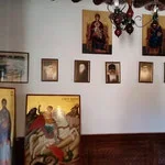 Gallery wall with framed artwork, portraits, and paintings in a room with a wooden floor.