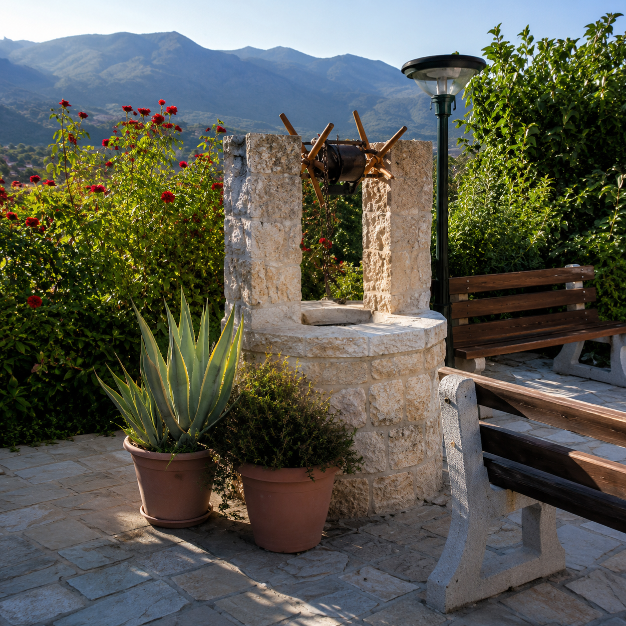 A lush garden scene with a stone well, two potted agave plants, a wooden bench, and a tall lamp post, with mountains in the background.
