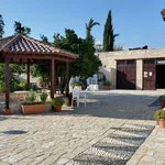 Outdoor courtyard with a small gazebo, potted plants, and a paved stone walkway in front of red brick buildings.