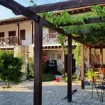 View of a residential backyard with a patio, pergola, greenery, and outdoor furniture.
