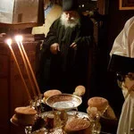 A priest celebrating a religious ceremony with candles and bread on an altar in a church