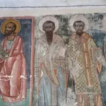 A mosaic depicting three religious figures with halos, dressed in ornate robes, standing side by side.