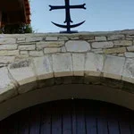 Stone archway with a wooden door beneath, and a metal torch holder on top of the arch.
