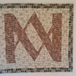 A mosaic tile with a stylized red letter 'M' on a beige background, framed by small black, gray, and white tiles.
