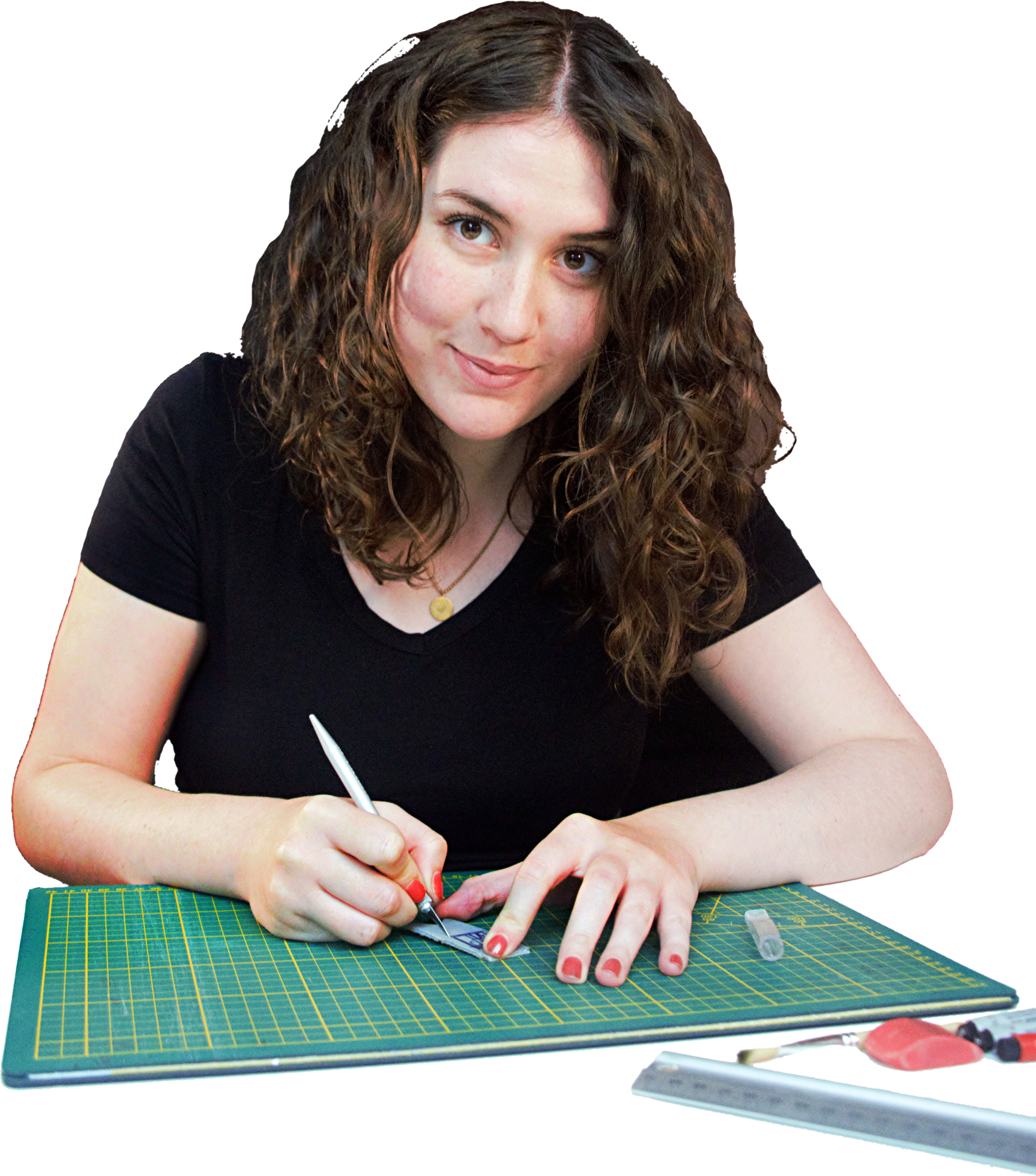 Woman in black shirt using a pen to sew or work on a fabric with a cutting mat on the table.