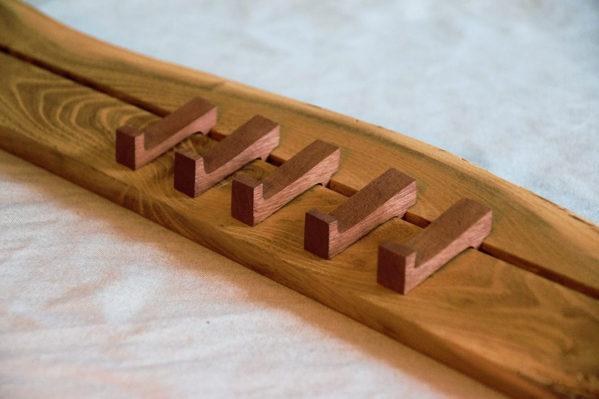 Close-up photograph of a handcreafted personal design of a wooden coathanger, lying on a light-colored fabric surface. Photographed and Created in Arnhem Cartref creative art studio