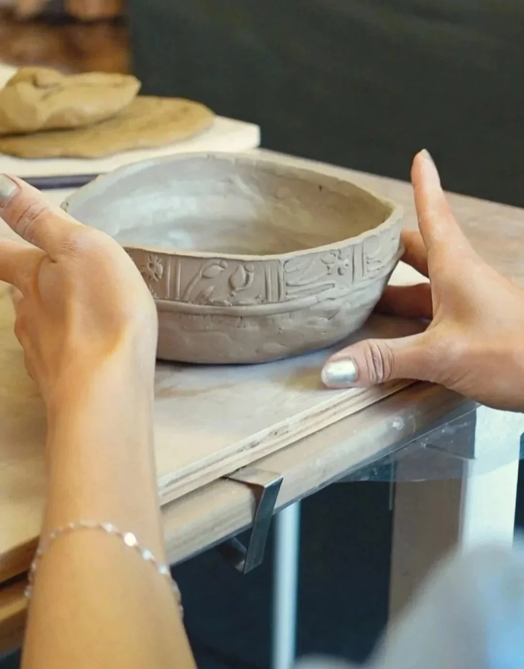 Person shaping a clay bowl on a pottery wheel.