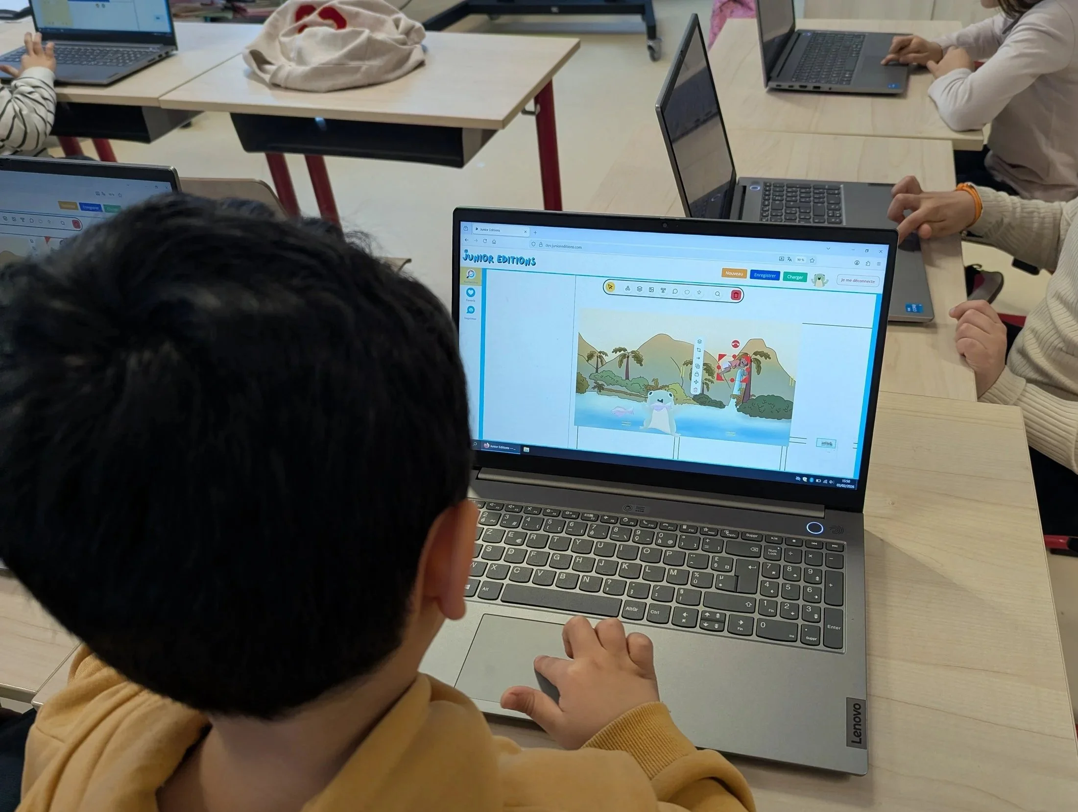 Un enfant assis devant un ordinateur portable, utilisant la plateforme pour enfants appelé 'Junior Éditions'.
