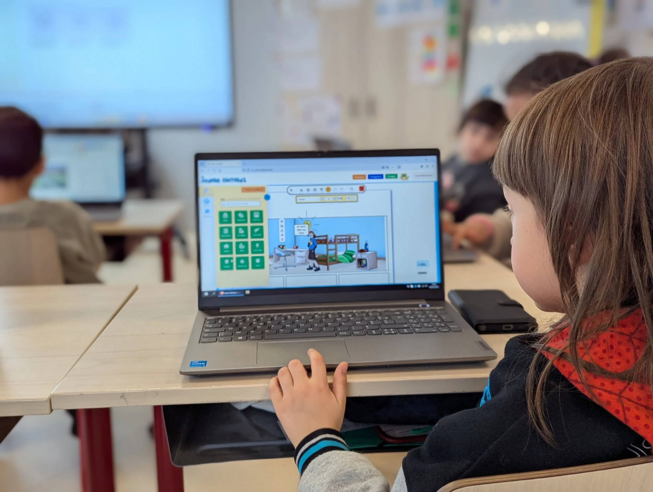 Un groupe d'enfants assis à des bureaux d'une salle de classe, utilisant des ordinateurs portables, la scène montre une ambiance éducative et numérique.