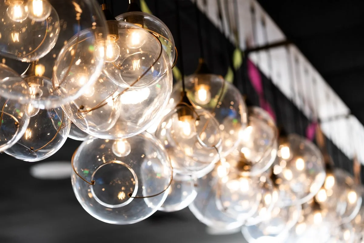 Multiple glass globe string lights hanging in a dark space, creating a decorative lighting display.