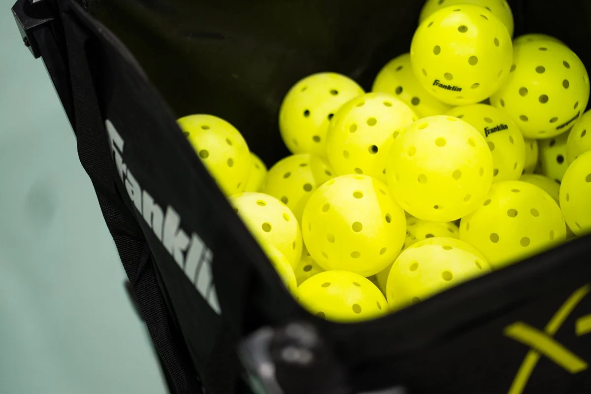 Yellow golf balls with black dots inside a black container.