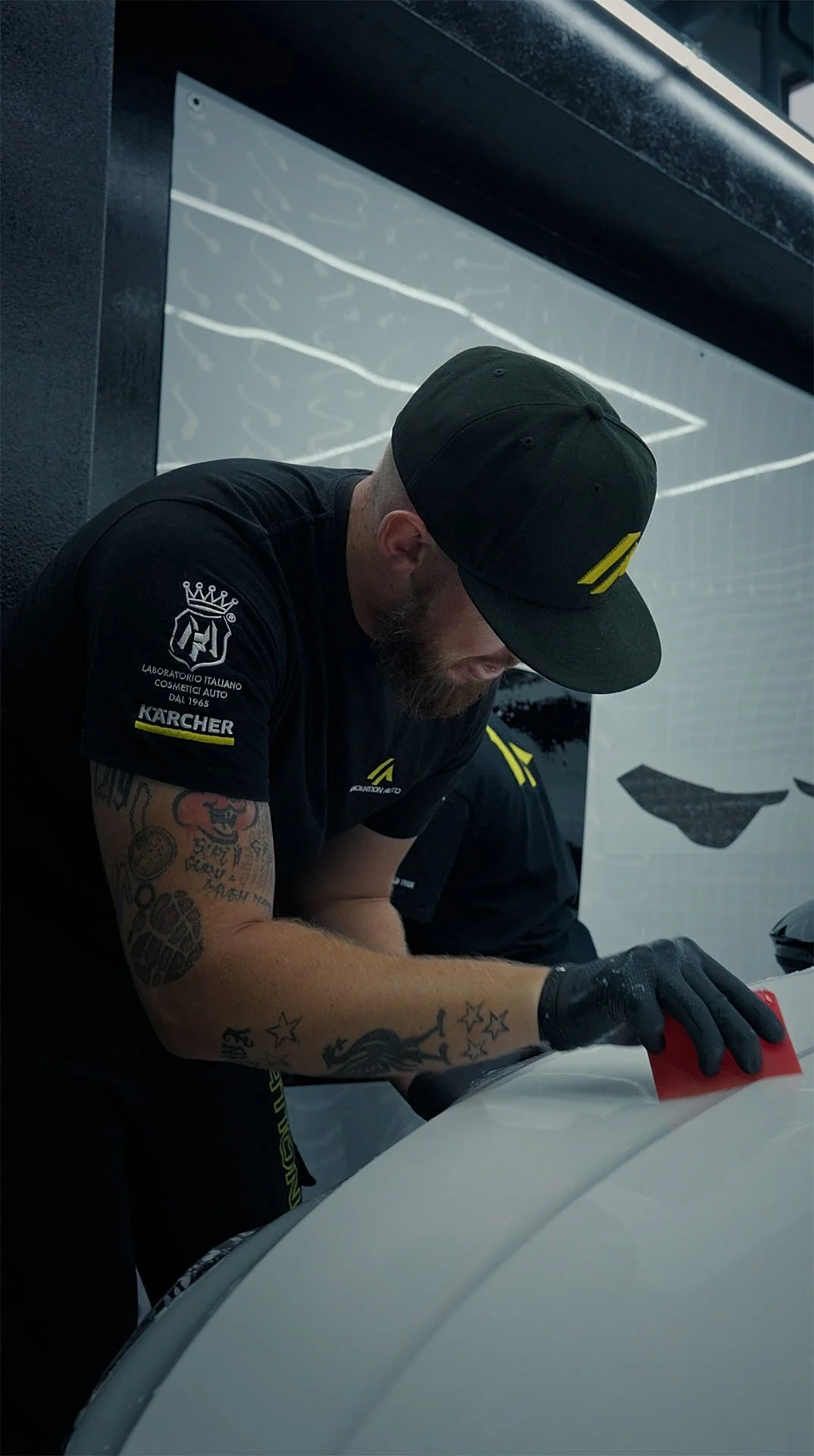 Installer working a squeegee across paint protection film on a white panel