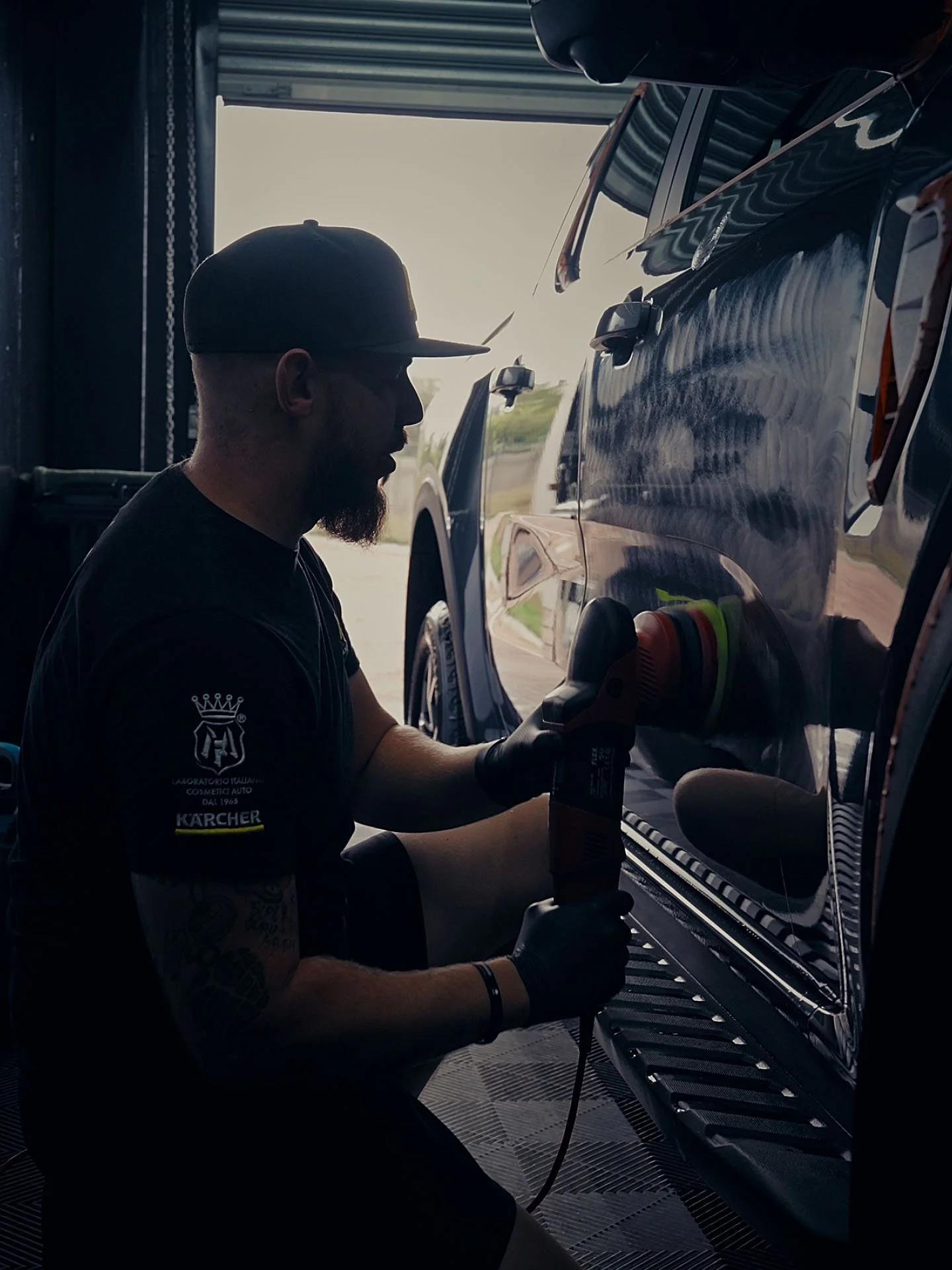Detailer machine-polishing a dark bonnet during paint correction