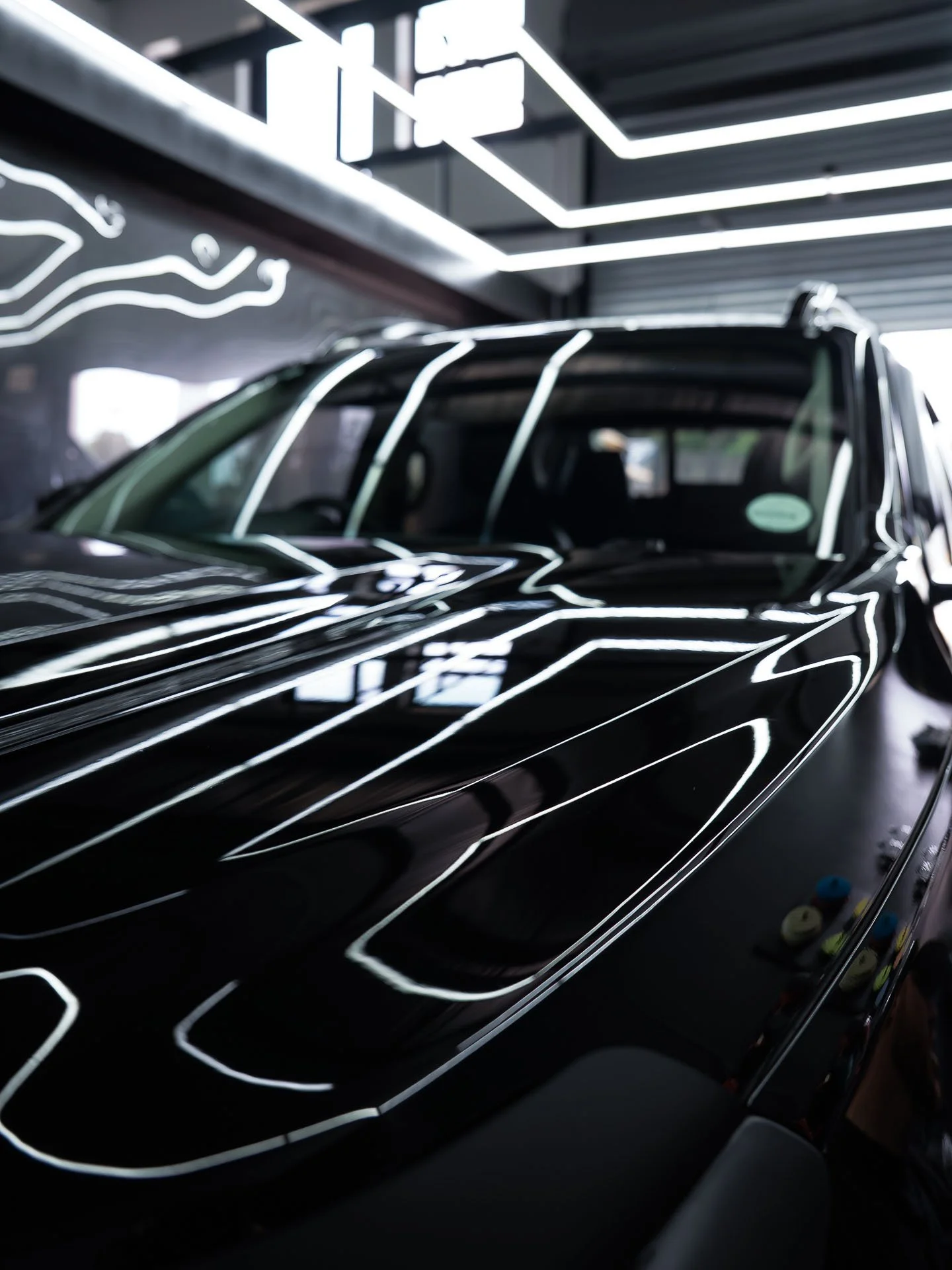 Black car under inspection lighting in the Innovation Auto workshop