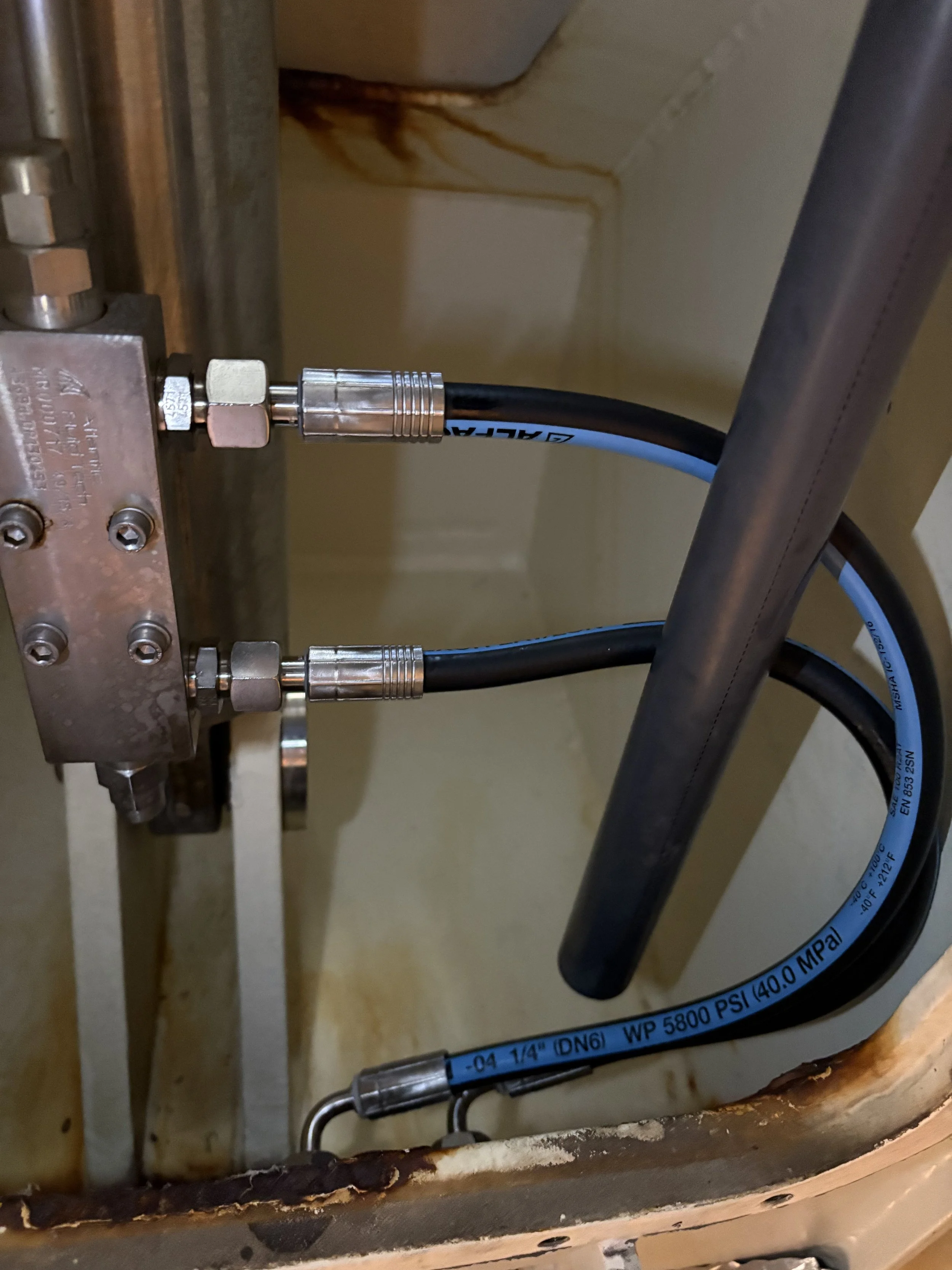 Close-up of 2 new hydraulic hoses, recently replaced.