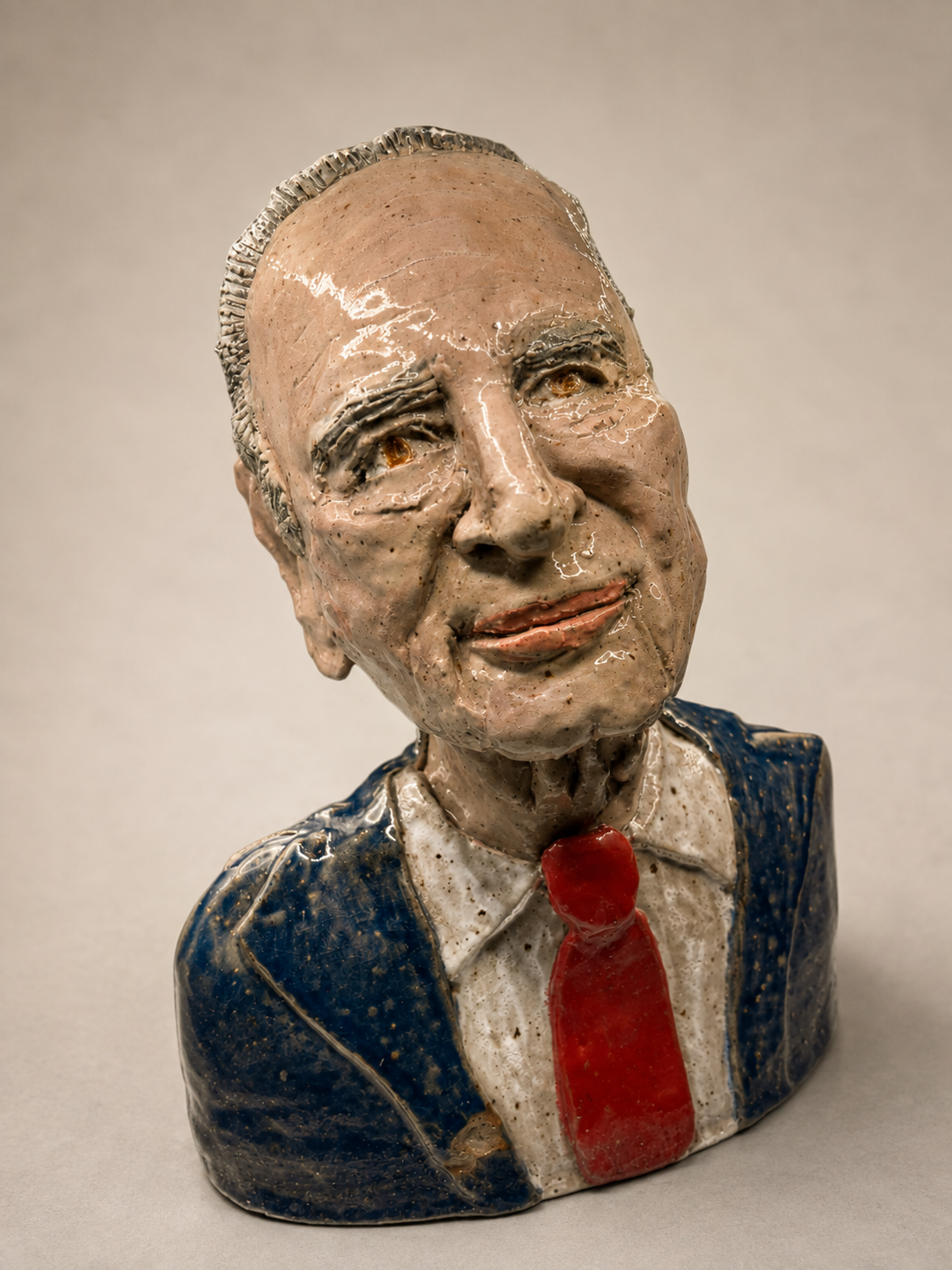 Glazed ceramic bust of an elderly man wearing a blue suit, white shirt, and red tie. Jewish famous people. Politics.