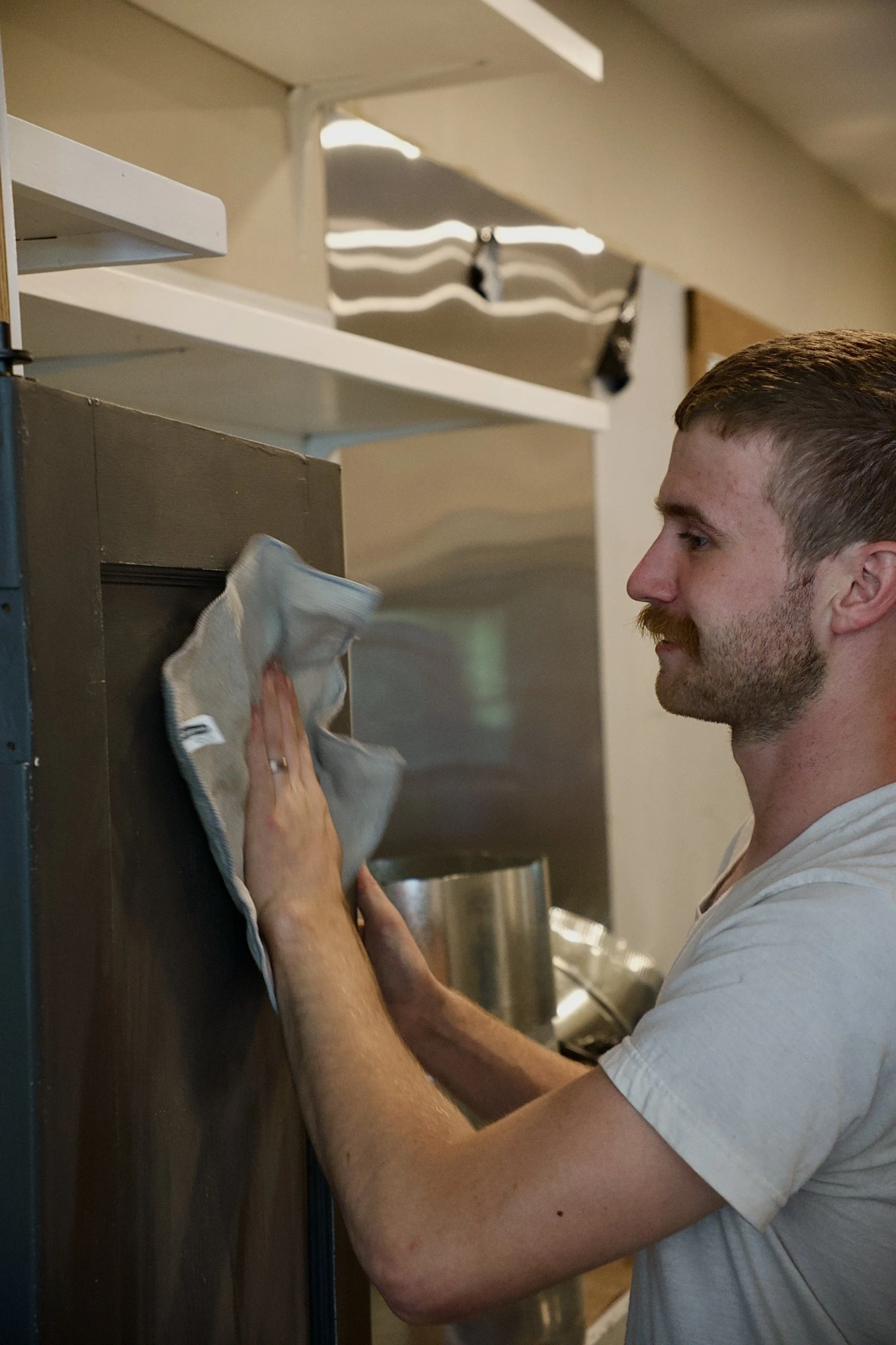 A man cleaning a surface with a cloth in an indoor setting.