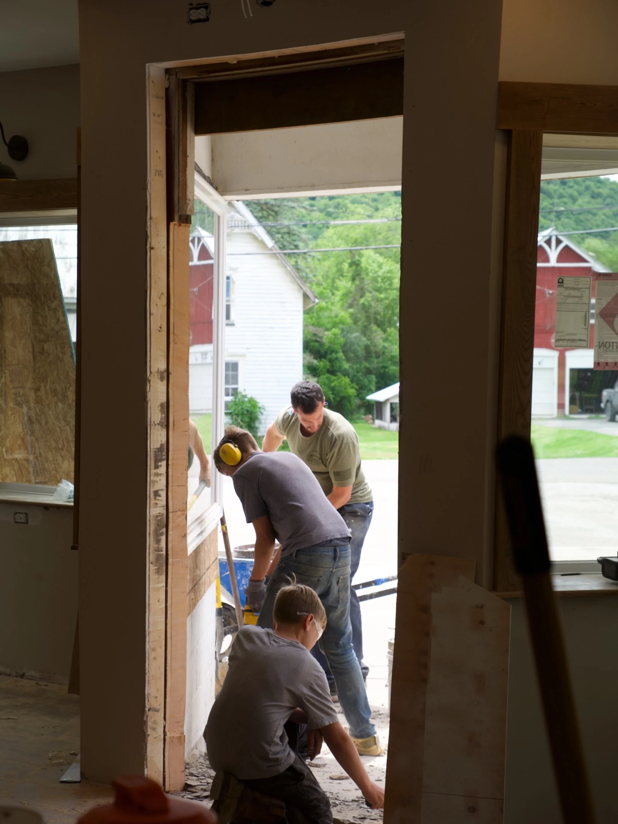 People working together on a construction or renovation project outdoors, seen through a doorway