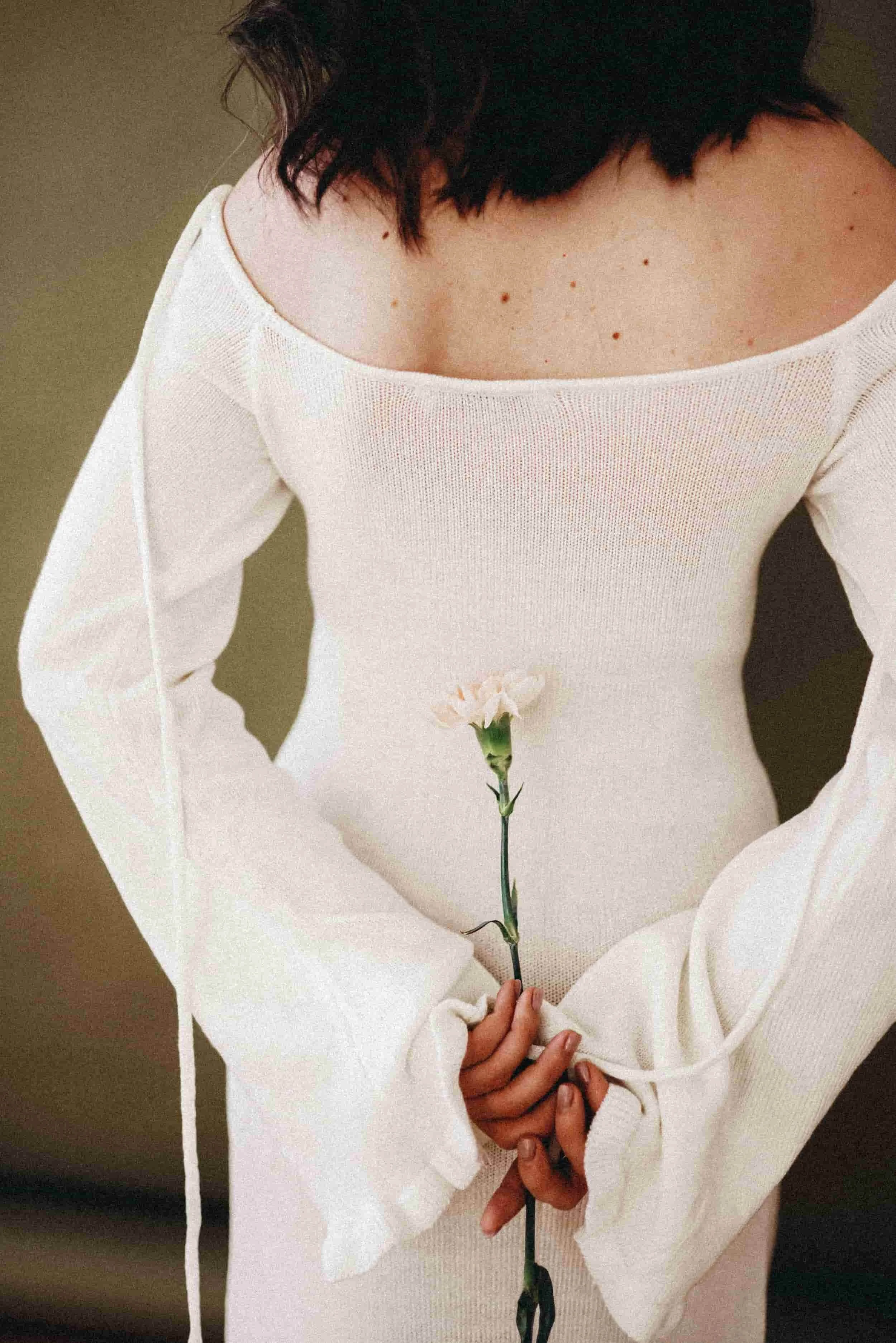 A woman holding a flower behind her back.