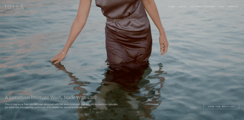 A woman standing in water, shown from her waist down, wearing a dark dress.